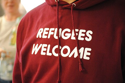 Dezember 2015: Die Willkommenskultur prägte auch das Engagement für Flüchtlinge in den Kirchengemeinden. Ein Mensch trägt rotes Sweat-Shirt mit der Aufschrift REFUGEES WELCOME