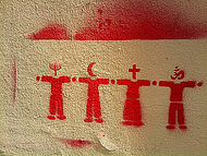 Streetart mit interreligiösen Symbolen, rotes Grafitti auf graubraunem Rauputz