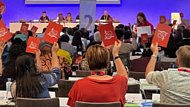 Auf dem Bild sind Menschen zu sehen, die Kärtchen zur Abstimmung über ein Thema hochhalten