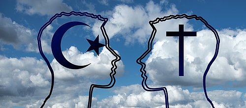 Das Bild zeigt die Silhouette zweier sich zugewandter Köpfe. Ein Kopf ist mit dem Symbol des Islam, ein Kopf mit dem christlichen Kreuz gekennzeichnet.